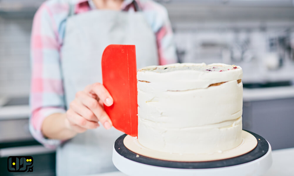 معرفی بهترین ابزار برای خامه کشی + تصویر شخصی در حال صاف کردن کیک با ابزار